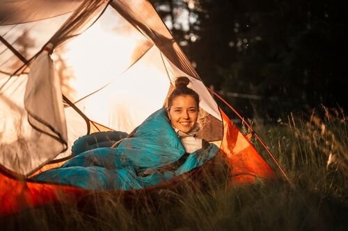 אישה בתוך שק שינה באוהל